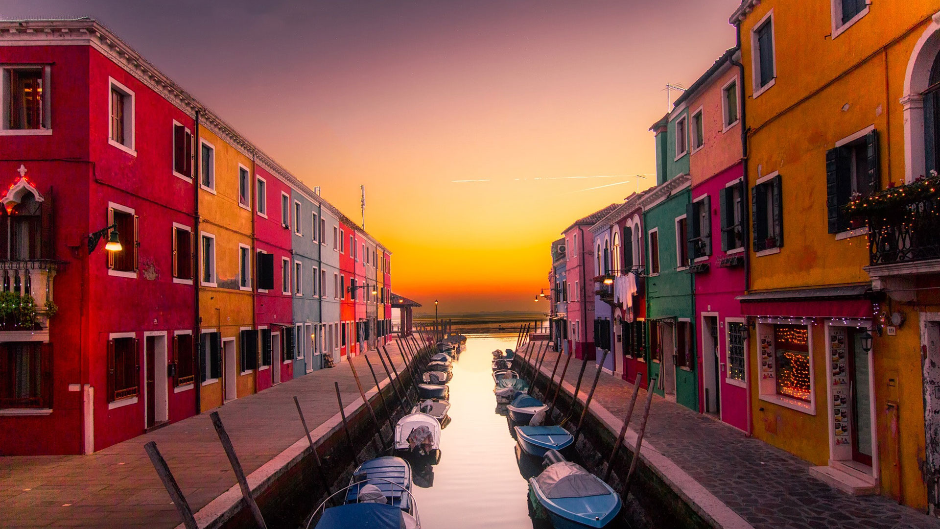 Brightly painted houses along a Burano canal at sunset