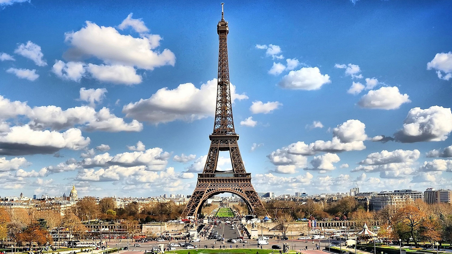 The Eiffel Tower in Paris under a blue sky with clouds