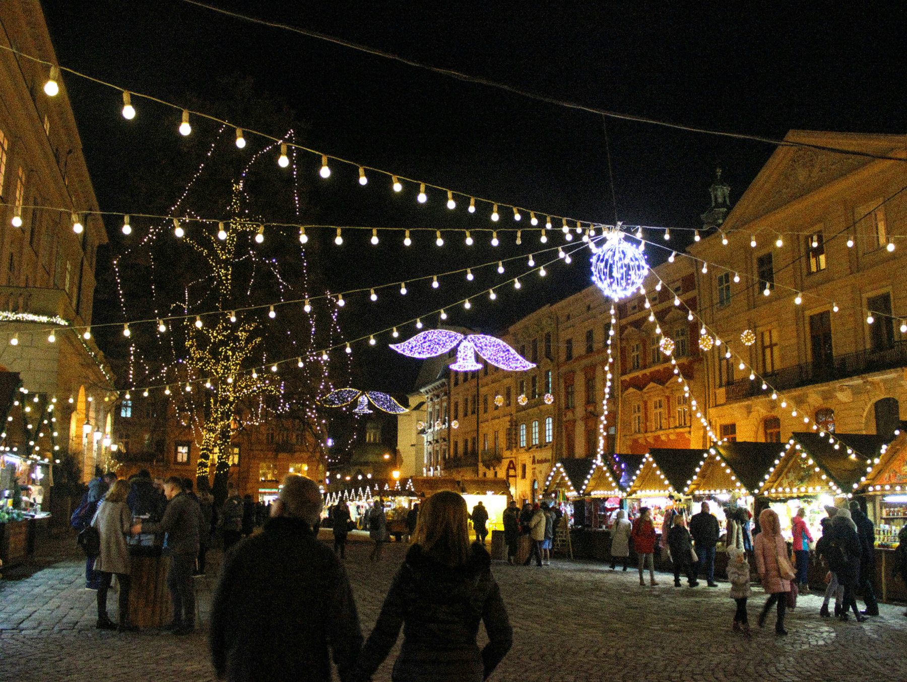 Christmas market stalls under strings of lights at night
