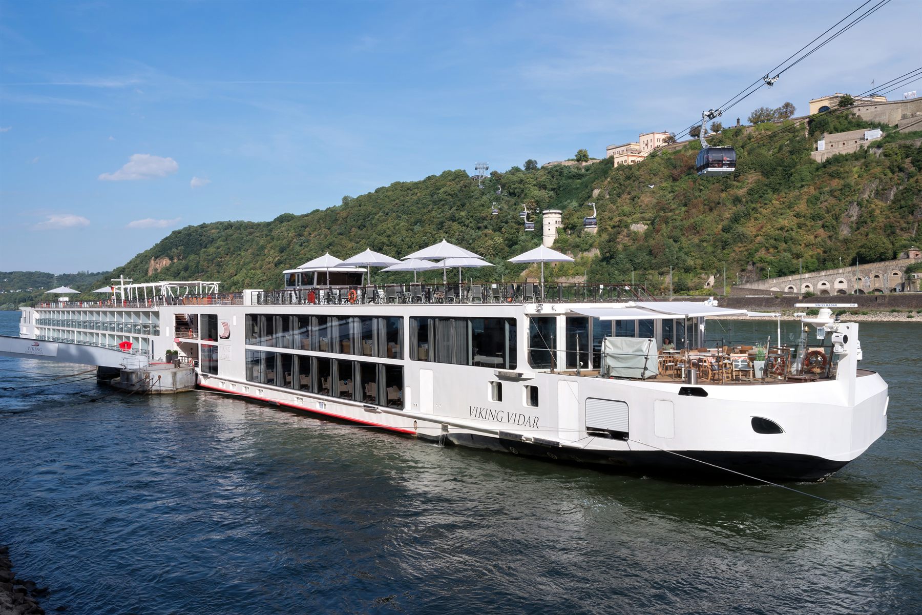 The Viking Vidar river ship moored below a wooded hillside with a cable car